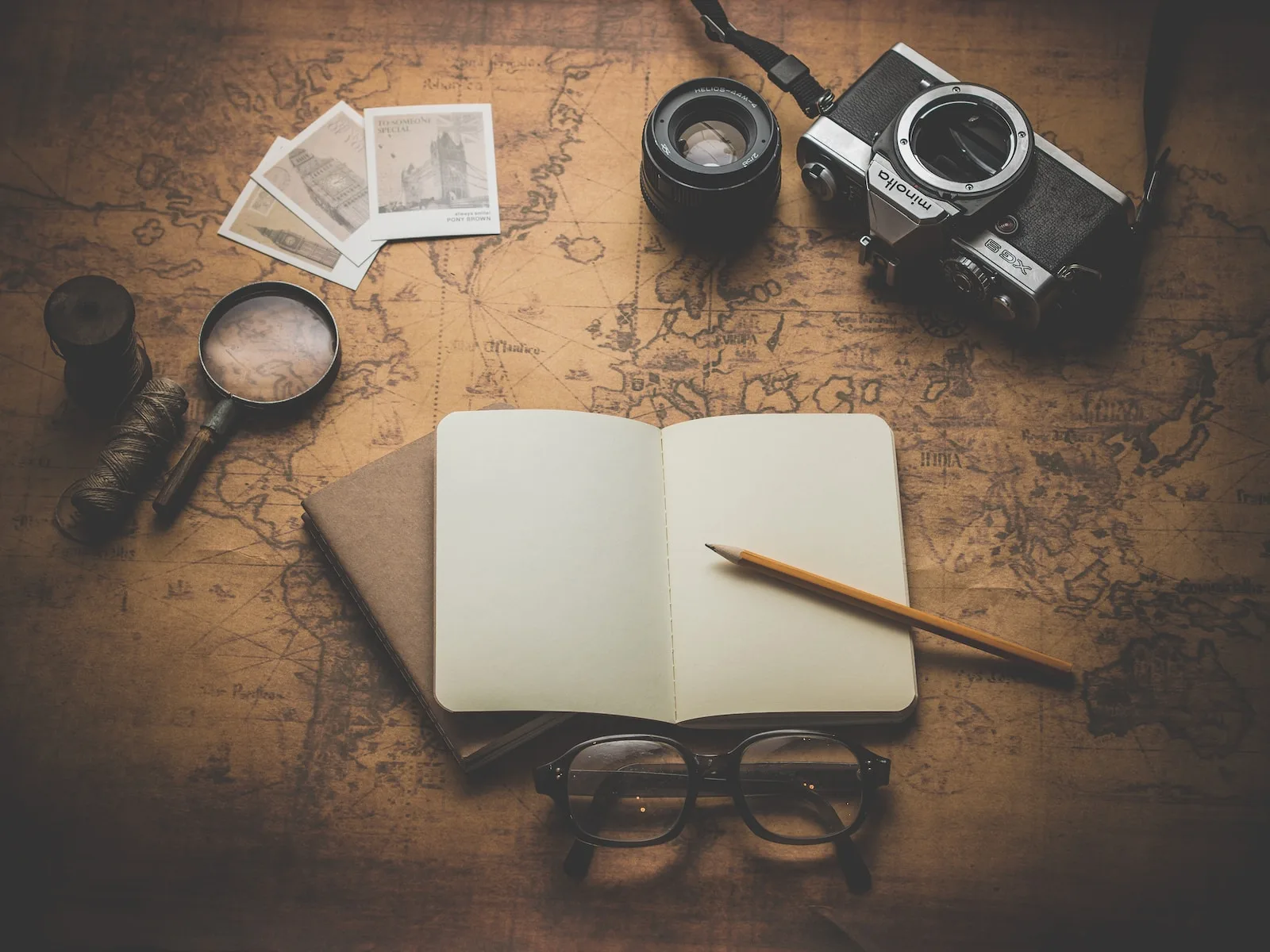 adventure map, flat ray photography of book, pencil, camera, and with lens