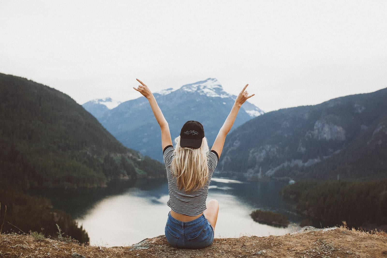 trading pay for remote work freedom, woman sitting on cliff raising both hands