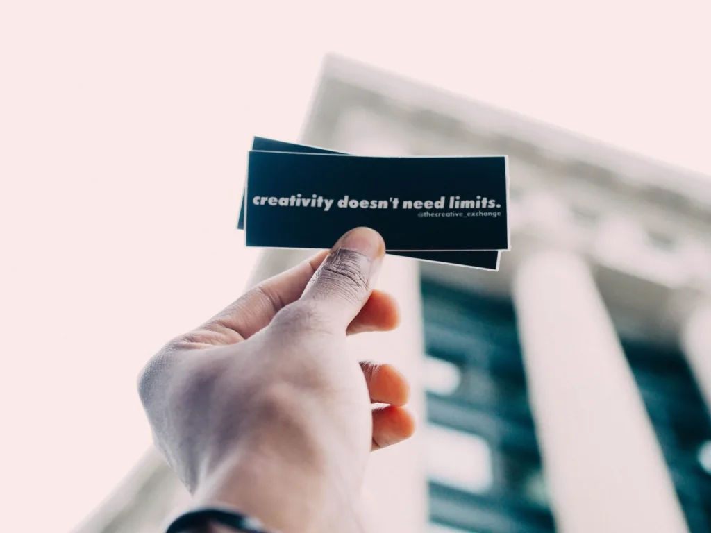 person holding black and white quote-printed card. creativity has no limits