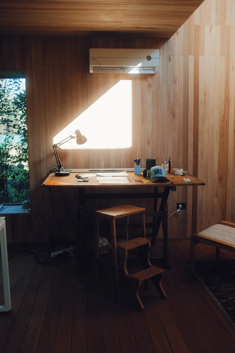 brown wooden table with black laptop computer on top creating a shed studio